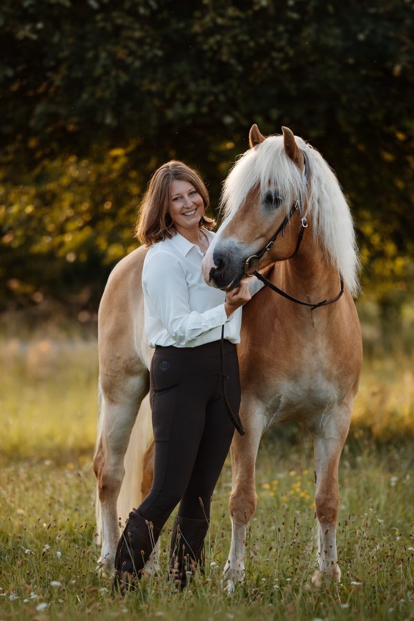 fotoshooting im sommer mit einer frau und ihrem haflinger im klassischen reitoutfit